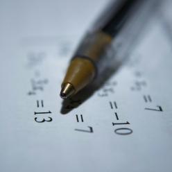 Pen sitting on a paper with math equations.