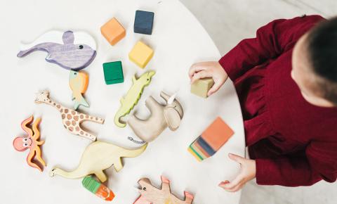 Little girl playing with colorful blocks on a white table