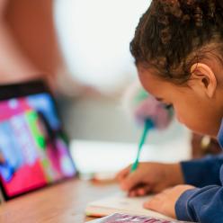 Young girl writing with iPad in front of her