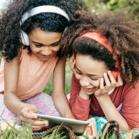 Two girls wearing headphones outside