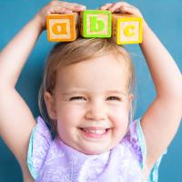 Smiling child holding letter blocks on their head