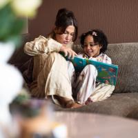 Parent reading to a child on the couch.