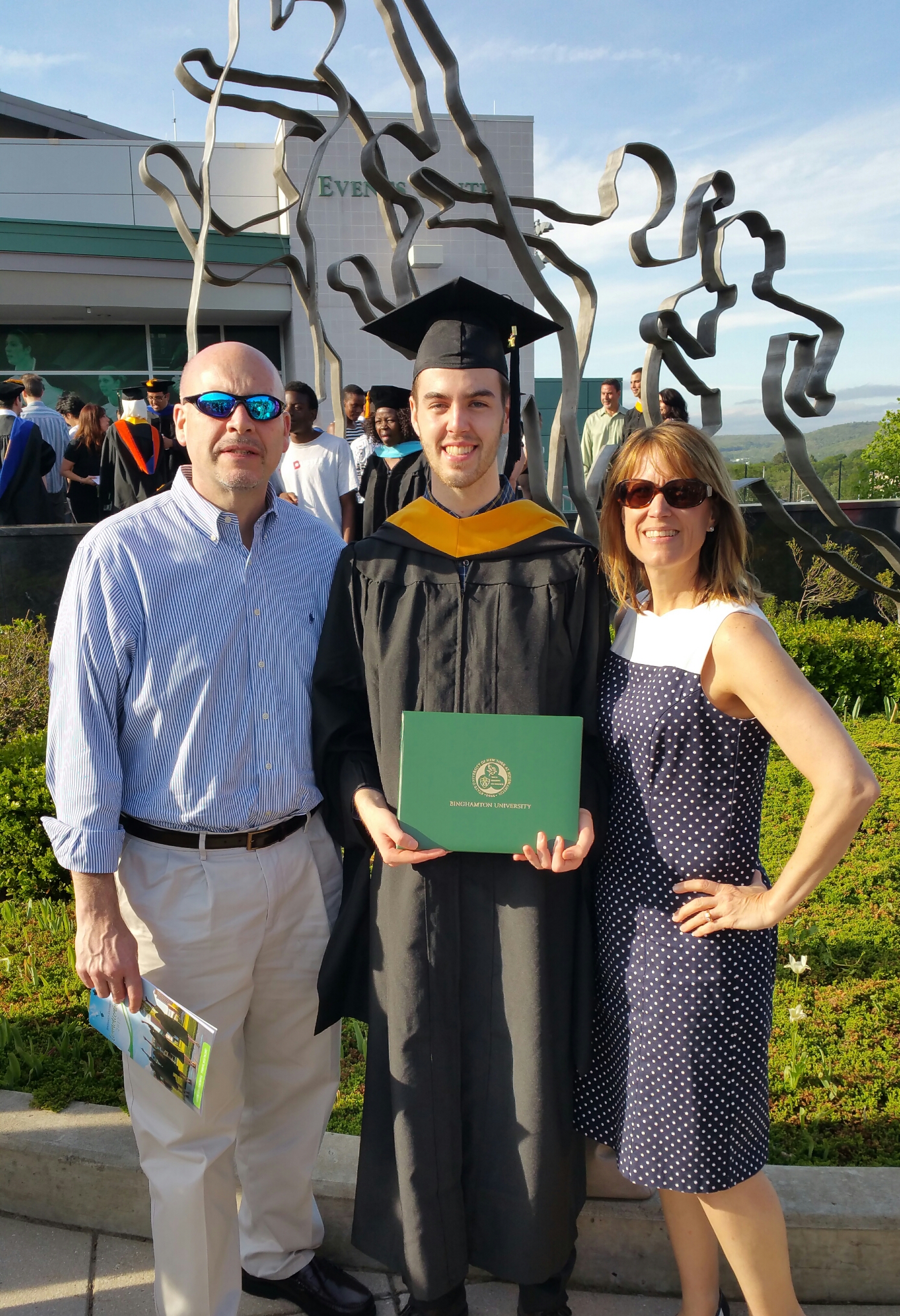 Susan and her husband with her son in his graduation gown.