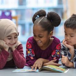 Three kids reading on library floor