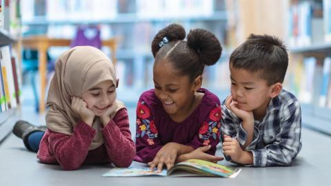 Three kids reading on library floor