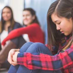 Upset girl sitting against lockers