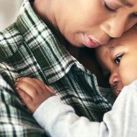 A worried mom is holding her child to her chest